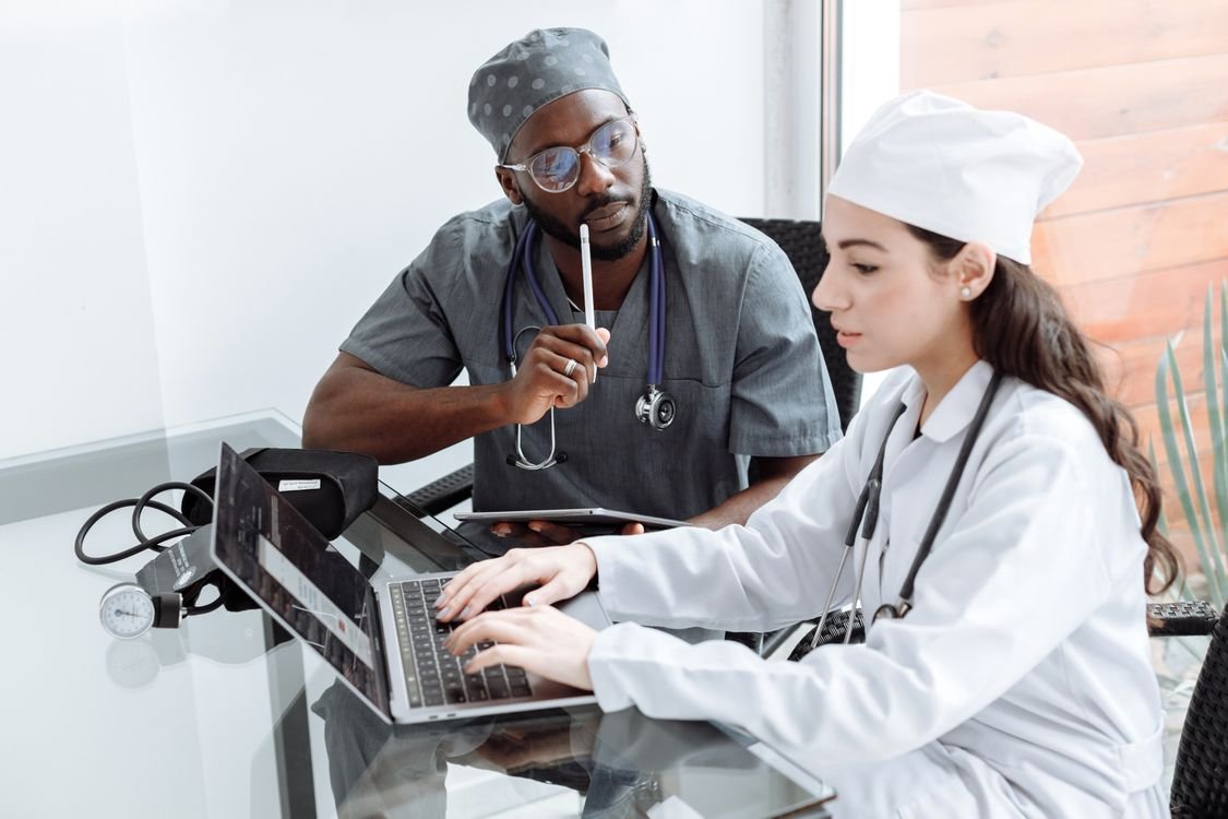 Profesionales de medicina con uniforme clínico estudian frente a un portátil.