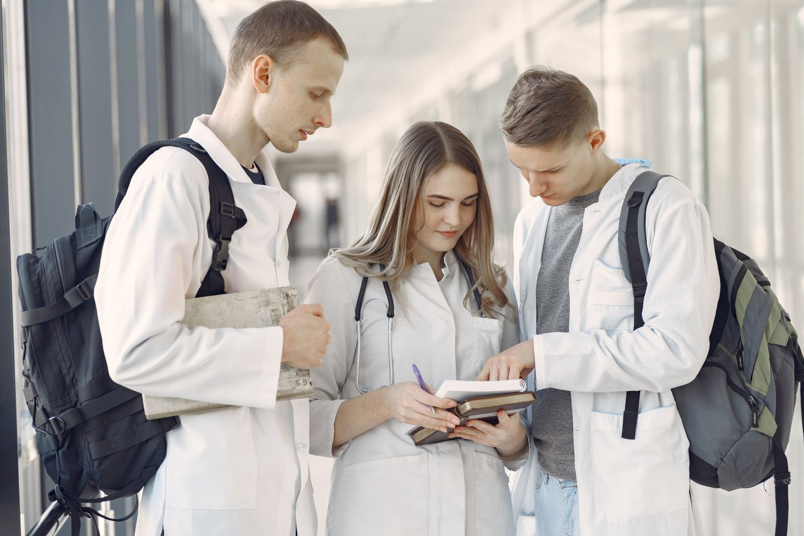 Tres estudiantes de medicina revisan sus notas en un pasillo.